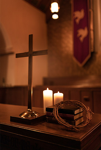 Altar con cruz de madera, corona de espinas, libros y velas para Ejercicios Espirituales