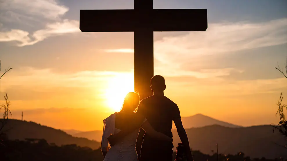 Matrimonio de espaldas contemplando la cruz de Cristo, símbolo del amor que también sufre.