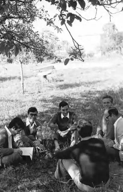 Joaquín Fernández sentado en círculo sobre el césped conversando con un grupo de jóvenes durante una jornada de convivencia.