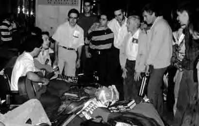 Joaquín Fernández sonriendo junto a un grupo numeroso de jóvenes durante una actividad al aire libre en el año 1991