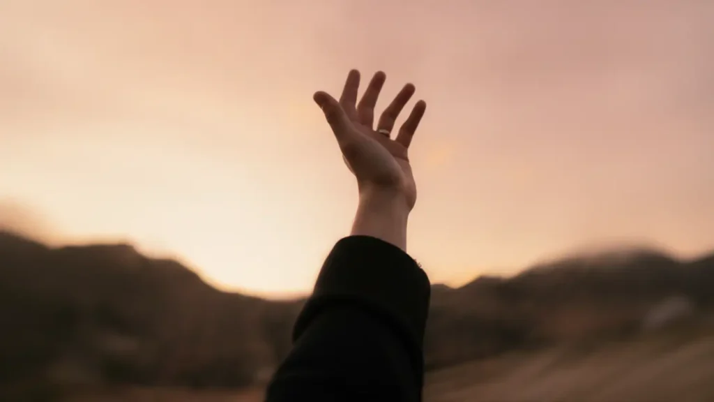 Mano de mujer en gesto de oración hacia el cielo para aprender a rezar con fe y esperanza.